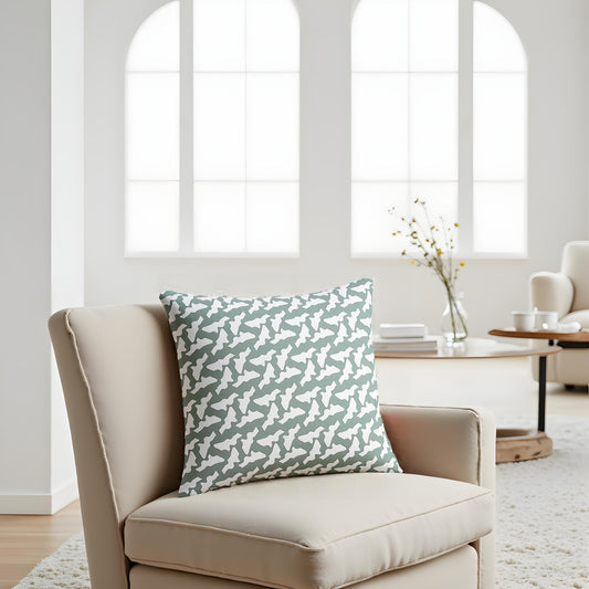 Beige armchair with a patterned green pillow in a bright room with large windows.