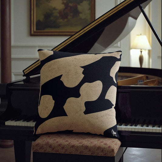 Decorative pillow with black and beige pattern on a piano bench in front of a grand piano.