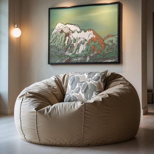 Beige bean bag chair with a patterned pillow in a room with a mountain painting on the wall.