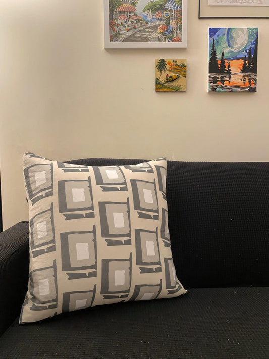Decorative pillow on a black couch with wall art in the background