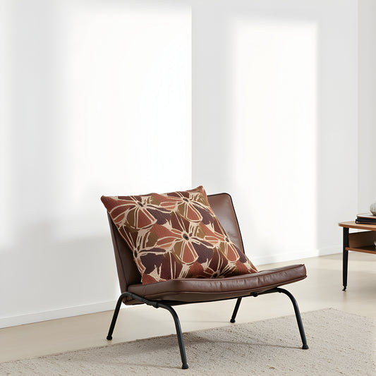 Brown leather chair with a patterned pillow in a minimalistic room.